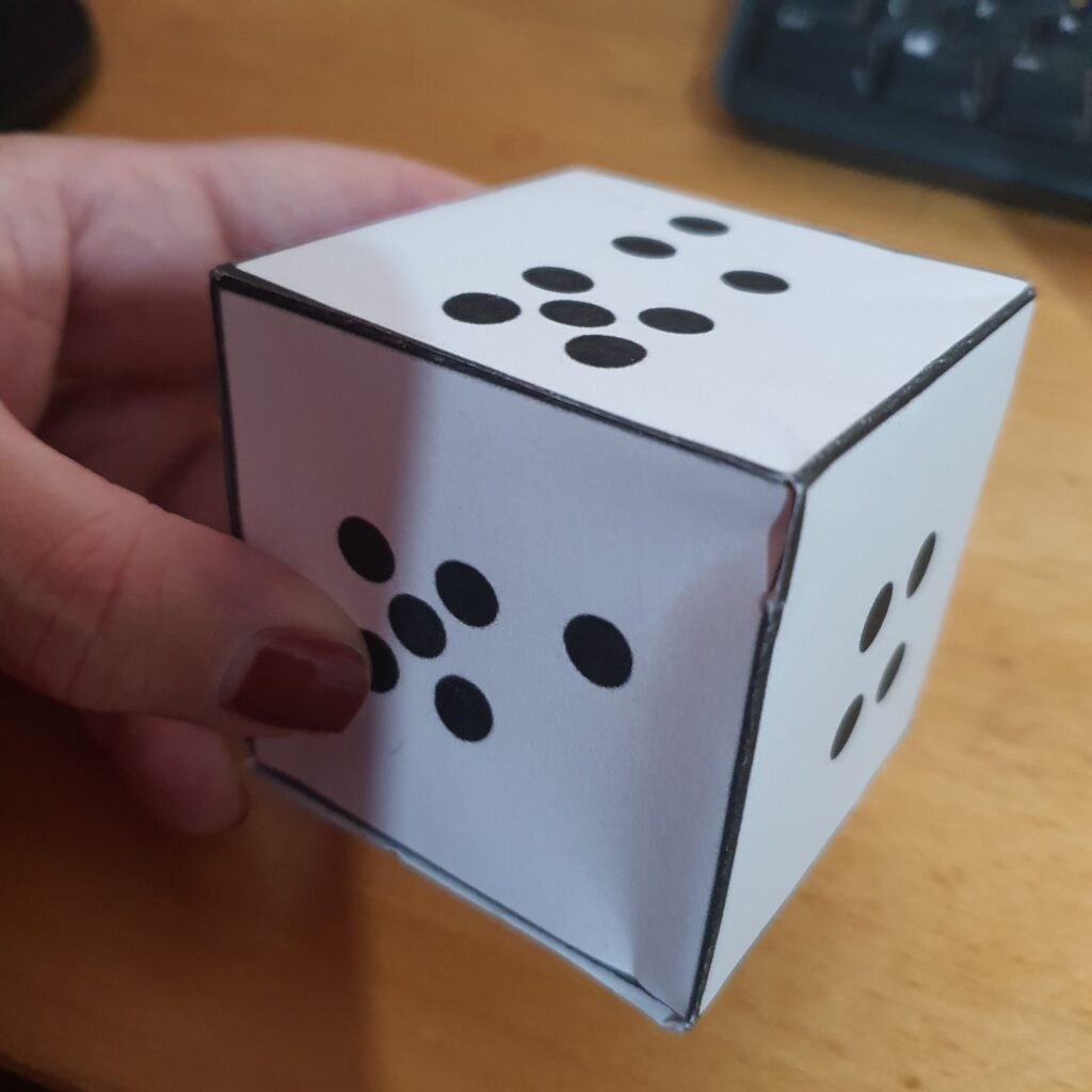 Judy holding a giant cardboard dice 